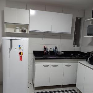 a kitchen with white cabinets and a white refrigerator at Apartamento Recreio p12 in Rio de Janeiro +13 photos