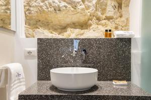La salle de bains est pourvue d'un lavabo et d'un mur en pierre. dans l'établissement Le Sirene B&B, à Raguse