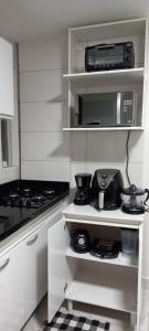 a white kitchen with a stove and a microwave at Apartamento Recreio p12 in Rio de Janeiro