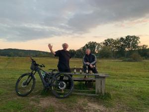 Due uomini seduti su una panchina vicino a una bicicletta di Kiek Inn a Hitzacker
