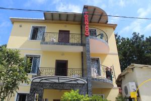 a yellow building with balconies and a red sign on it at Tornado Hotel in Ureki