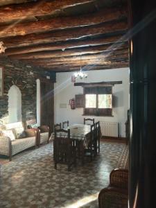 a dining room with a table and chairs and a couch at La Posada del Altozano in Lanteira