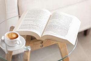 an open book on a glass table with a cup of coffee at Le Sirene B&B in Ragusa