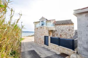 an old stone building with a gate next to the ocean at House Sea Stone in Dobropoljana