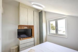 a bedroom with a bed and a tv and a window at House Sea Stone in Dobropoljana