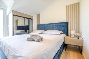 a bedroom with a large white bed with a blue headboard at House Sea Stone in Dobropoljana