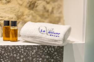 un asciugamano e due bottiglie di oli essenziali su una mensola di Le Sirene B&B a Ragusa