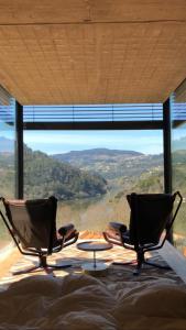 two chairs and a table in front of a large window at Dajas Douro Valley - Exclusive Villas in Sande