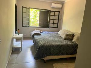 um quarto com uma cama e uma janela em Casa grande no Guarau em Peruíbe