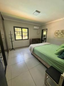 um quarto com uma cama verde e uma janela em Casa grande no Guarau em Peruíbe