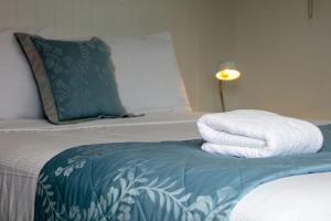 a bed with two towels sitting on top of it at Joy's Rest Cabin - Whangamata in Whangamata