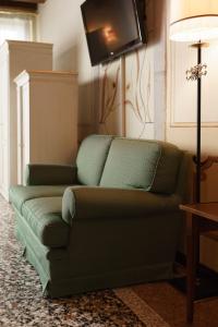 a living room with a green couch and a tv at Hotel Villa Policreti in Castello dʼAviano