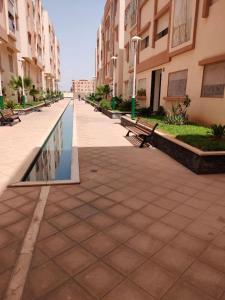 um pátio com bancos e uma piscina reflectora num edifício em Appartement Résidence avec piscine intérieure et Piscine couverte em Marrakech