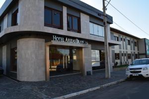 a building with a car parked in front of it at Hotel Areias Brancas in Rosário do Sul