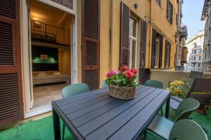 un tavolo in legno con un cesto di fiori sul balcone di 227 - Largo Zecca Luxury Apartment - Nel cuore del centro di Genova a Genova