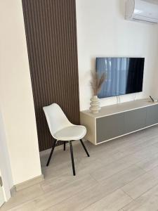 Cette chambre comprend une chaise blanche et une télévision. dans l'établissement DA apartments, à Varna