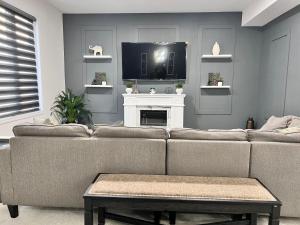 a living room with a couch and a tv at Spacious 4-Bedroom Home, Comfortably Sleeps 10 in Barrie