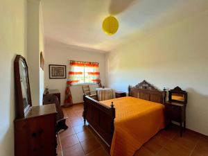 a bedroom with a bed with an orange blanket on it at Casa da Horta in Canha