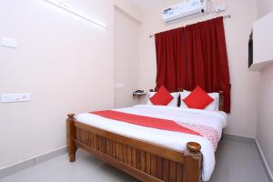 1 dormitorio con 1 cama con cortina roja en OYO Flagship Viswa Towers, en Madurai