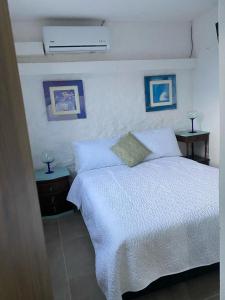 1 dormitorio con 1 cama blanca y 2 mesitas de noche en La Casona Llanera, en San Martín