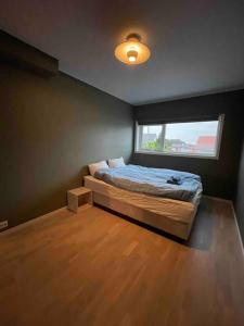 um pequeno quarto com uma cama e uma janela em Rekkehus sentralt i Bryne em Time