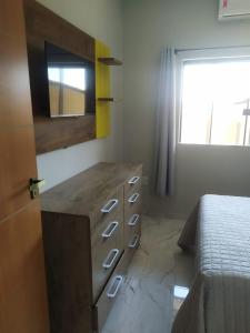 a bedroom with a dresser and a bed with a window at Novo Horizontes in São João del Rei