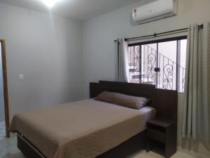 a bedroom with a bed and a window with a balcony at Novo Horizontes in São João del Rei