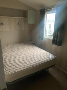 a small bed in a room with a window at Spruce Ridge 86, Blue Dolphin in Gristhorpe