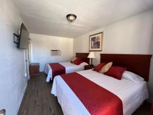 a hotel room with two beds with red and white sheets at Arizona 9 Motor Hotel in Williams