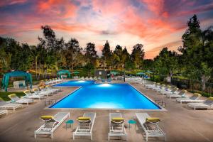 a swimming pool with lounge chairs and a sunset at Oceanside Beach style King & 2 queen beds in Oceanside
