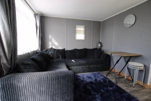 uma sala de estar com um sofá preto e uma mesa em Beautiful Chalet close to the beach em Eastchurch