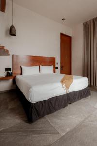 a bedroom with a large bed with a large white bedspread at Prana Boutique Hotel Tulum in Tulum