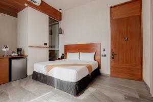 a bedroom with a large bed and a wooden door at Prana Boutique Hotel Tulum in Tulum