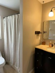 a bathroom with a white shower curtain and a sink at Last Mango in Palm Coast in Palm Coast