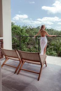 Una mujer con un vestido blanco parada en un balcón en Prana Boutique Hotel Tulum en Tulum