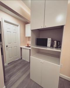 una pequeña cocina con armarios blancos y microondas en Guest House Baltimore County en Parkville