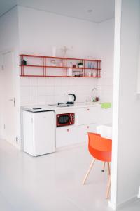 a white kitchen with a sink and a red chair at Идеальный домик для отдыха in Almaty