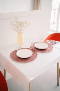 Идеальный домик для отдыха في ألماتي: طاولة بيضاء عليها صحنين و مزهرية