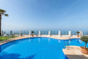 a large swimming pool with the ocean in the background at Cozy beachfront 2BR with Terrace, Pool and Garage in Sitio de Calahonda