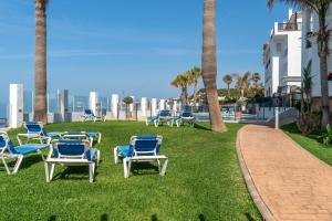 a group of chairs sitting on the grass near the beach at Cozy beachfront 2BR with Terrace, Pool and Garage in Sitio de Calahonda