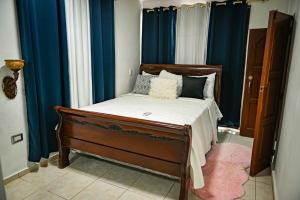 een slaapkamer met een bed met blauwe gordijnen bij Lily House 3 in San Felipe de Puerto Plata