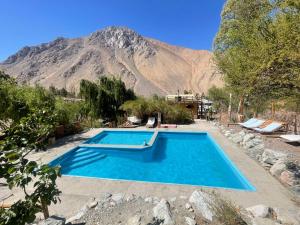 a swimming pool with a mountain in the background at elquiwellness Cochiguaz in Cochiguaz