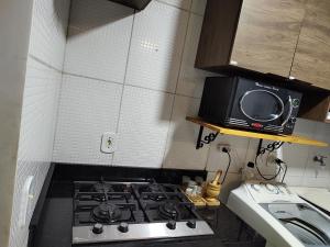 eine kleine Küche mit einem Herd und einer Mikrowelle in der Unterkunft Rota Beach-Aeroporto l ortobom queen l ar cond l tv smart l wi-fi l cozinha completa in Maceió