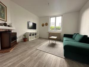 a living room with a green couch and a television at Maison plain pied au calme proche centre d’Orléans in Orléans