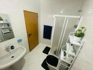 La salle de bains blanche est pourvue d'un lavabo et d'une douche. dans l'établissement Apartamento Oliveira House Rent, à Praia
