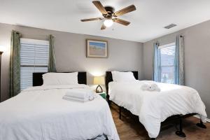 Duas camas num quarto com lençóis brancos e uma ventoinha de tecto. em Tranquility - A Birdy Vacation Rental em San Antonio