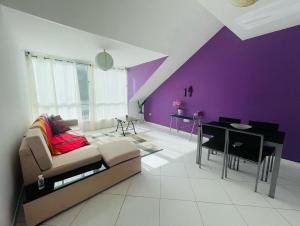 - un salon avec un canapé et un mur pourpre dans l'établissement Apartamento Oliveira House Rent, à Praia
