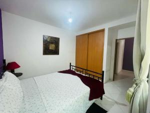 - une chambre avec un lit blanc et une armoire en bois dans l'établissement Apartamento Oliveira House Rent, à Praia