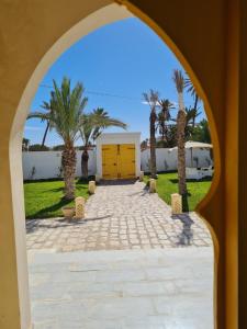an arched doorway to a driveway with palm trees at Musk de djerba suite aziz avec piscine in Temlale