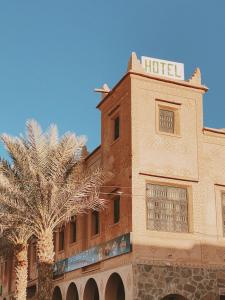 a hotel with a palm tree in front of a building at Kasbah Ennakb in Nkob